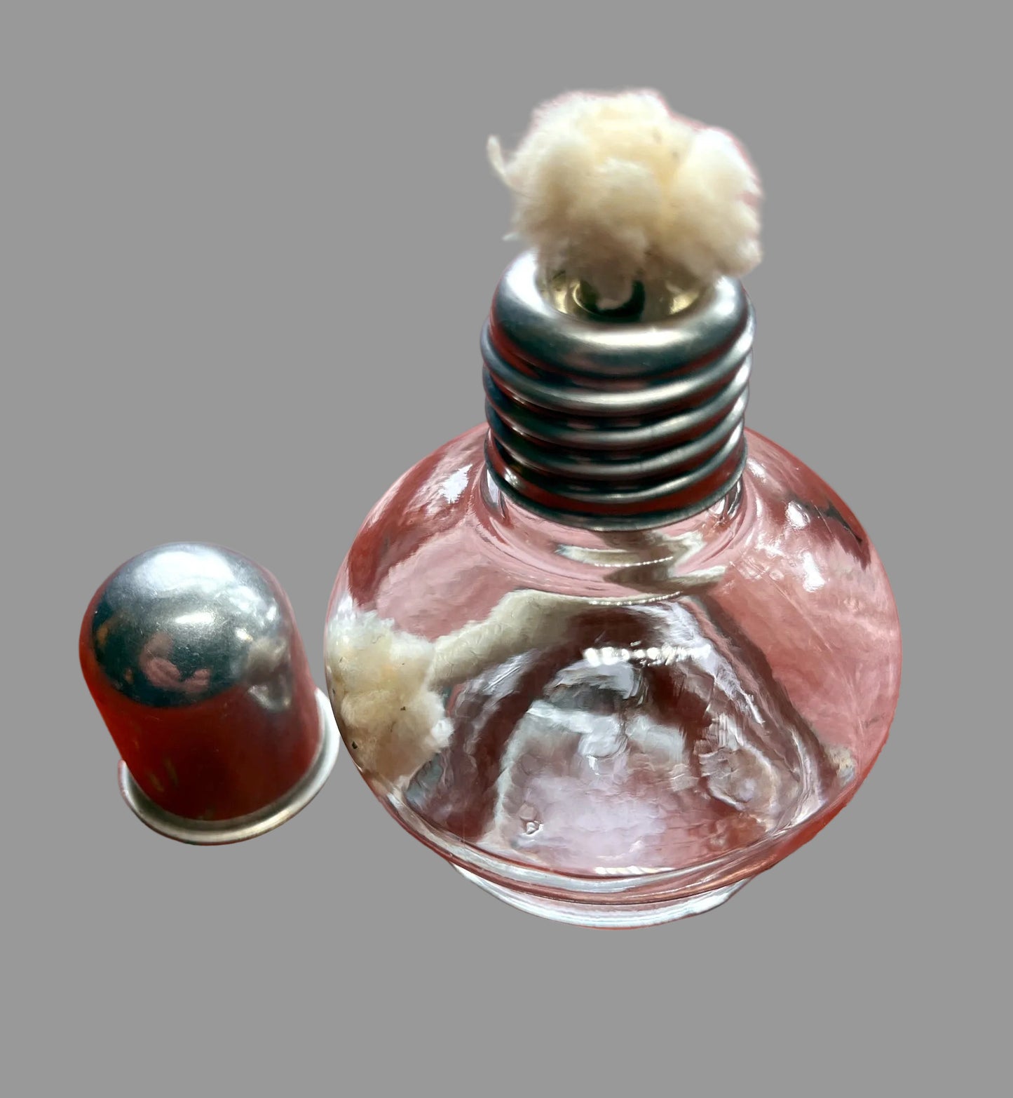 Clear glass bottle with metal cap on a red wooden surface
