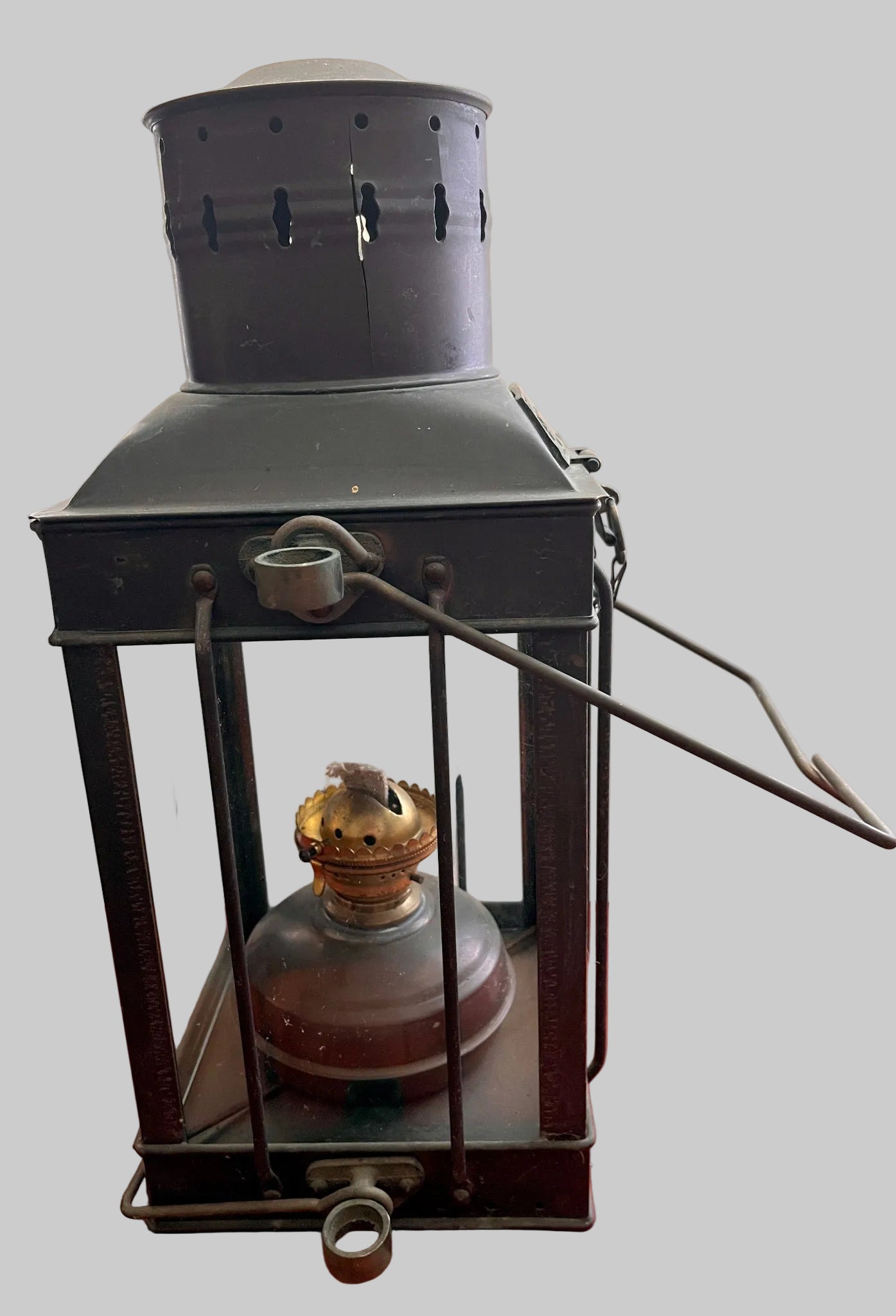 Vintage-style metal lantern with oil lamp on a red surface