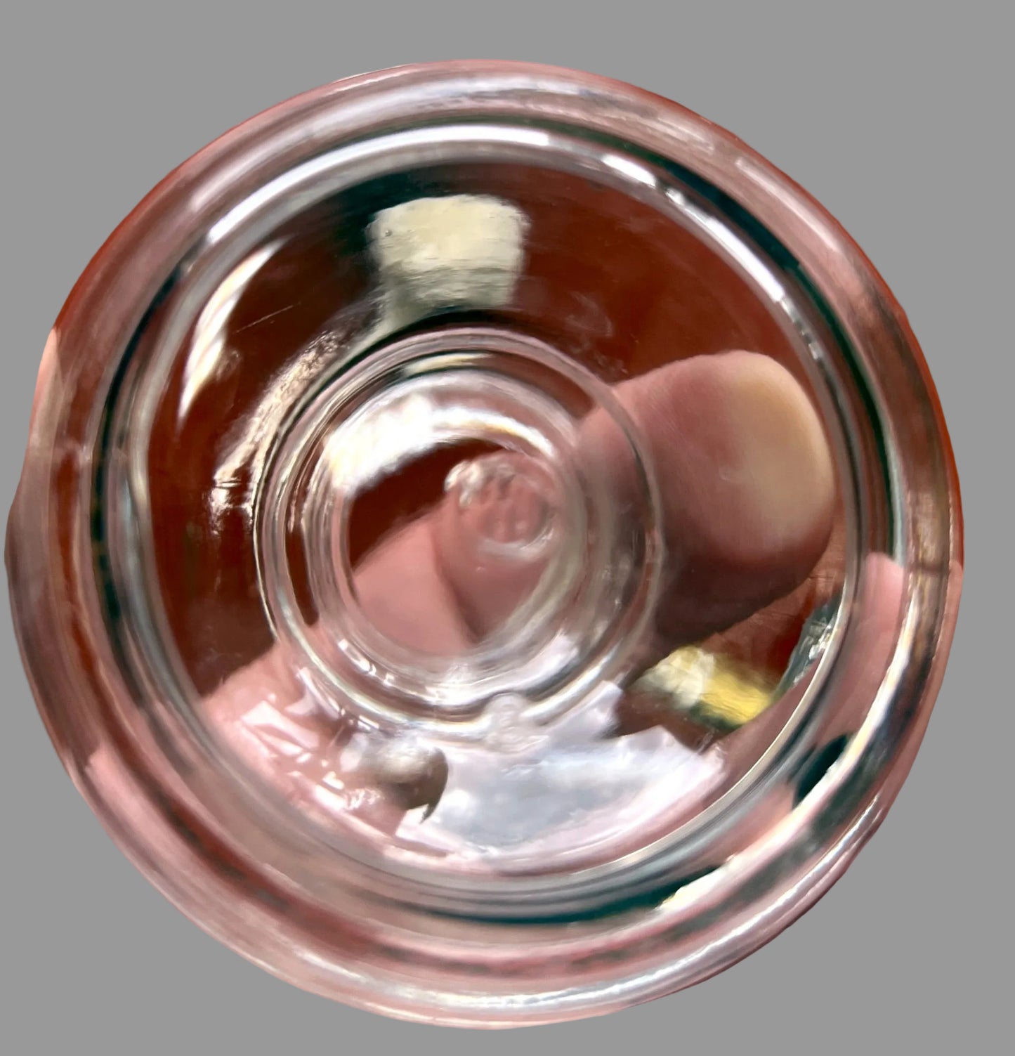 Clear glass bowl held in a hand with a wooden surface in the background