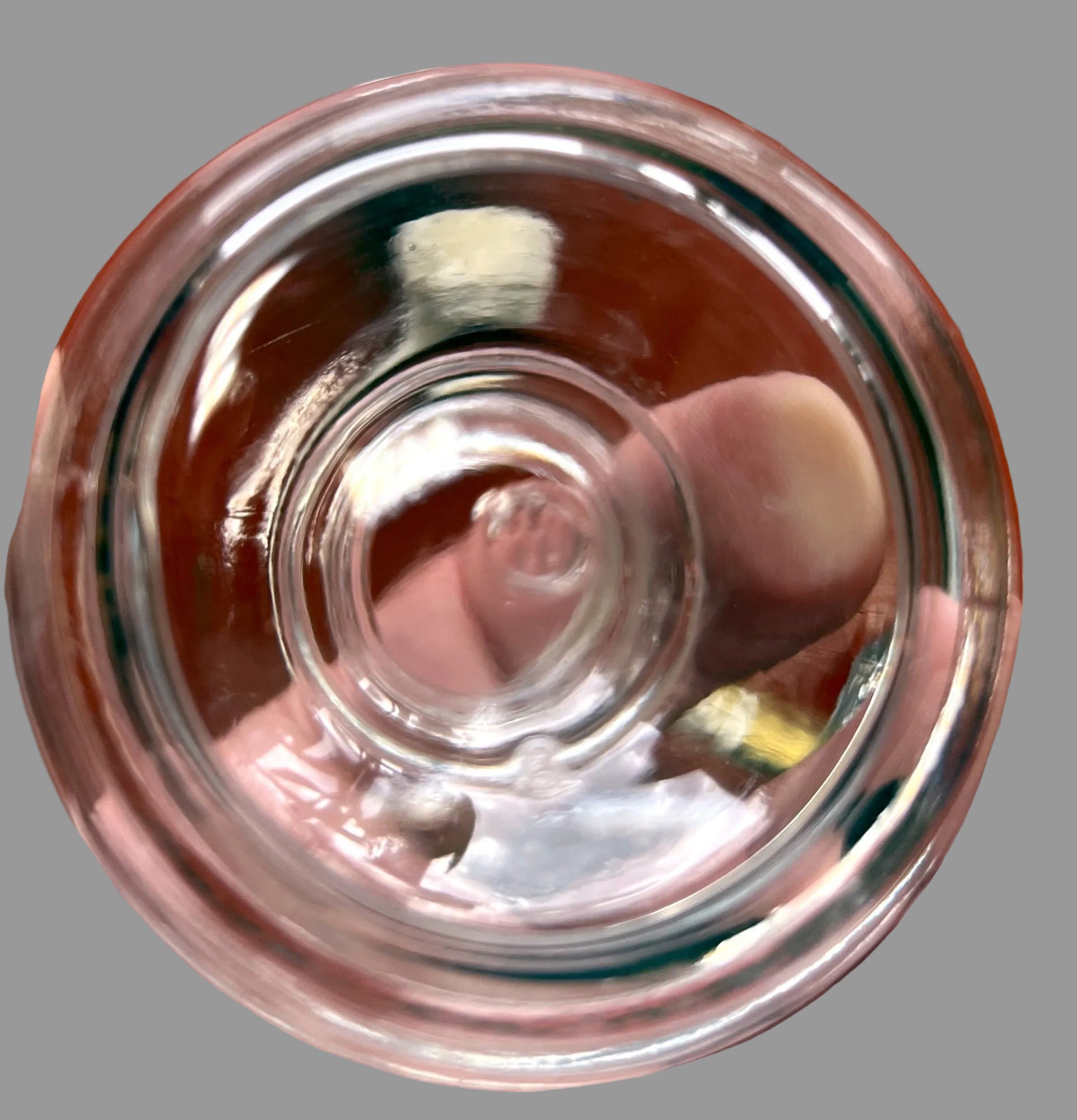 Clear glass bowl held in a hand with a wooden surface in the background