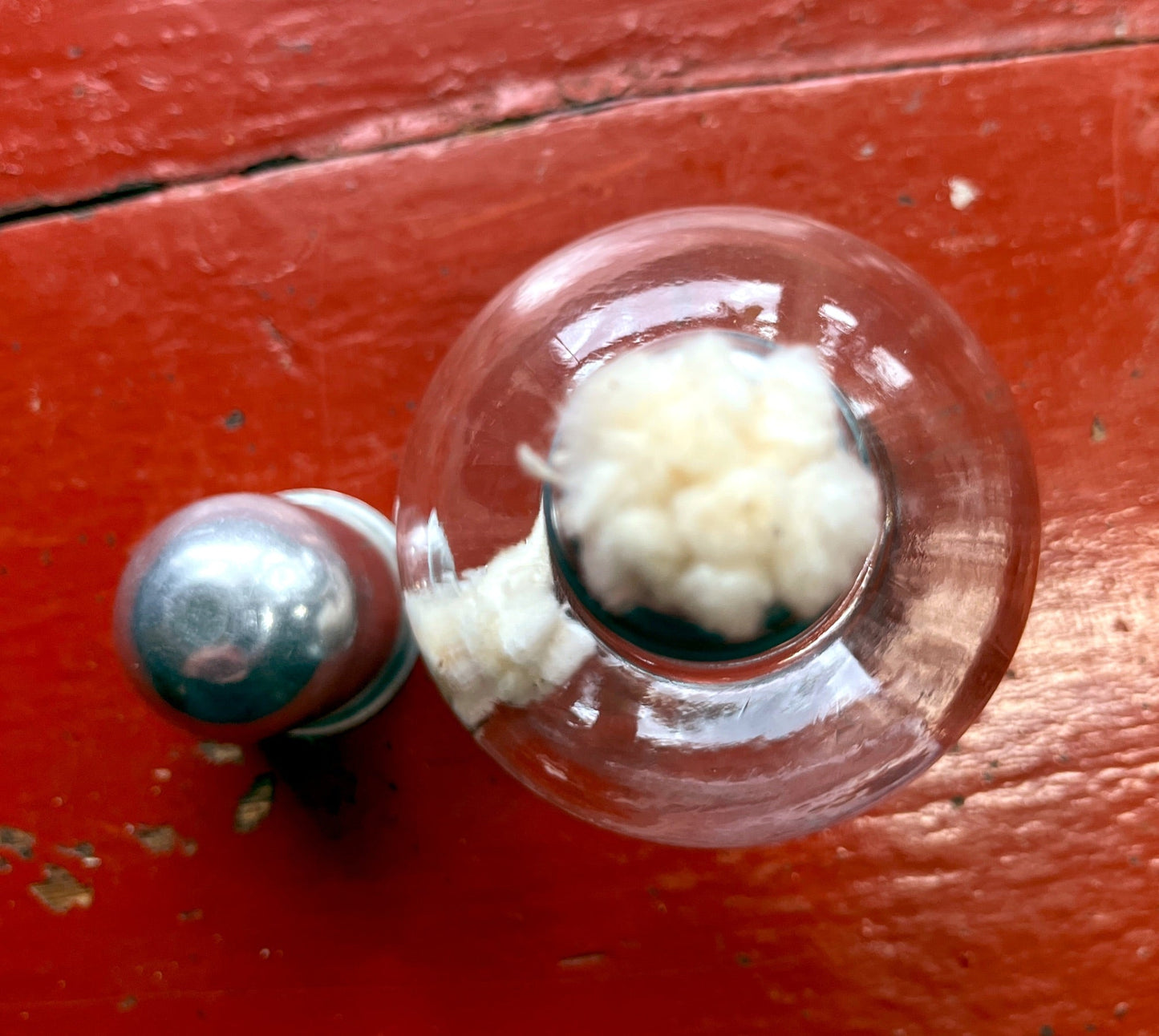 Close-up of a glass container with white substance on a red wooden surface