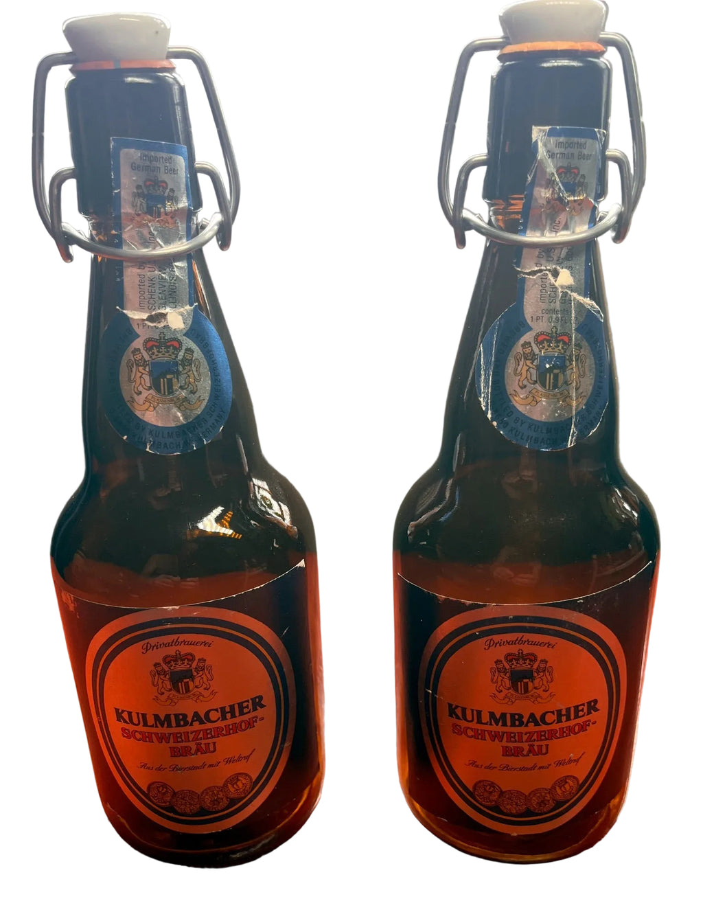 Two Kulmbacher beer bottles on a wooden surface with a blurred background