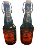 Two Kulmbacher beer bottles on a wooden surface with a blurred background
