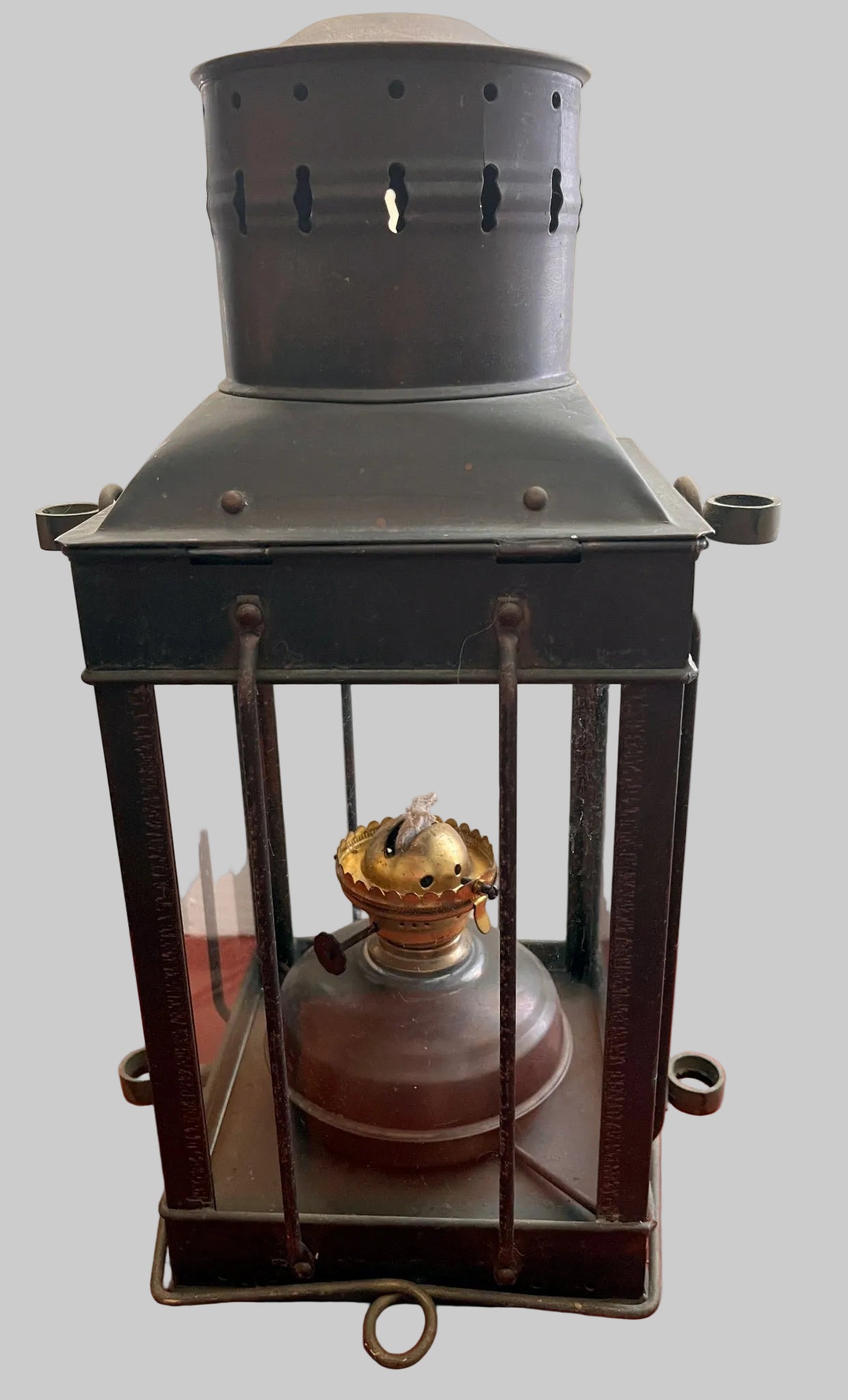 Vintage-style oil lantern on a red surface with a plain background