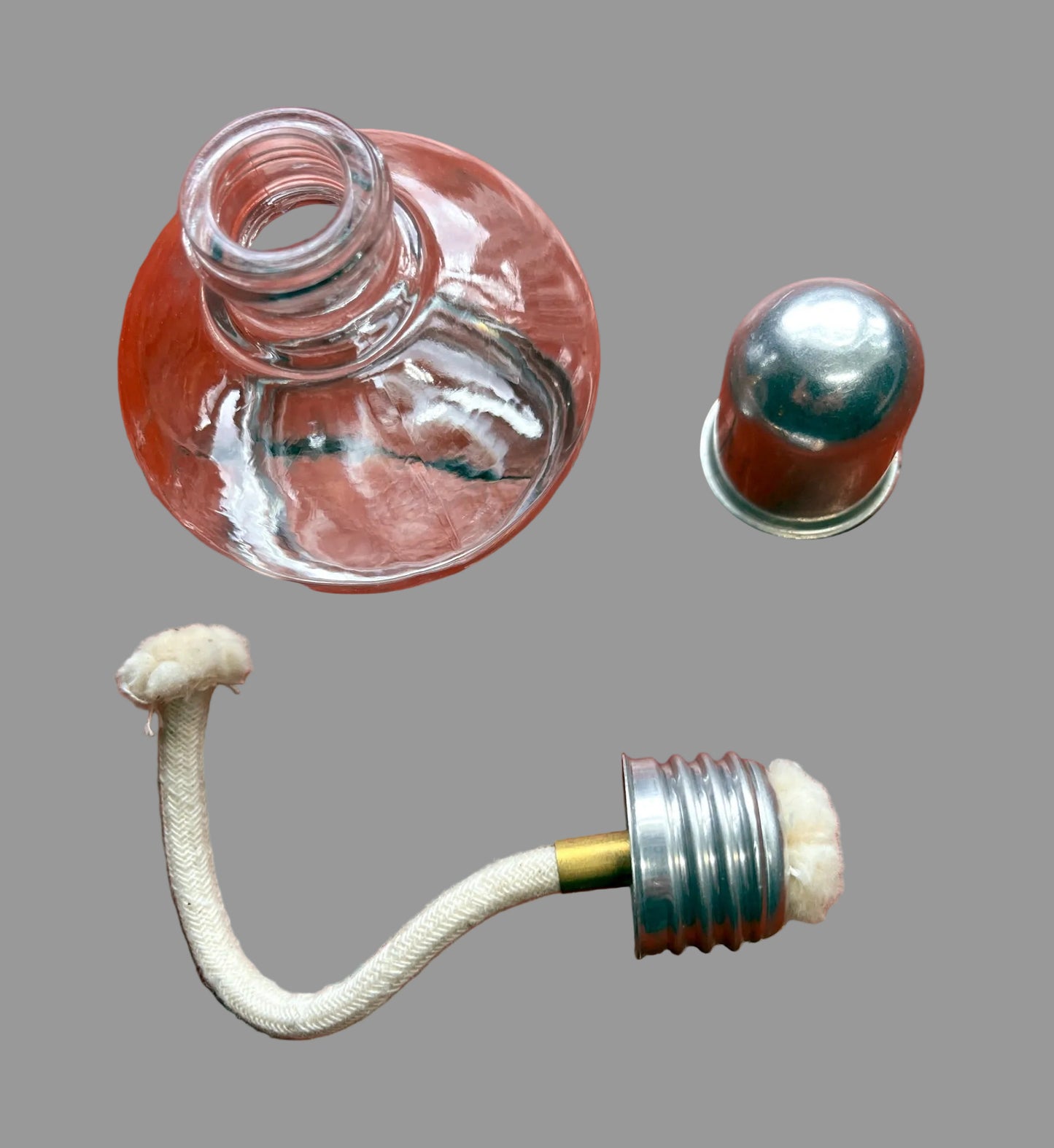 Clear glass bottle with metal cap and white rope on a wooden surface